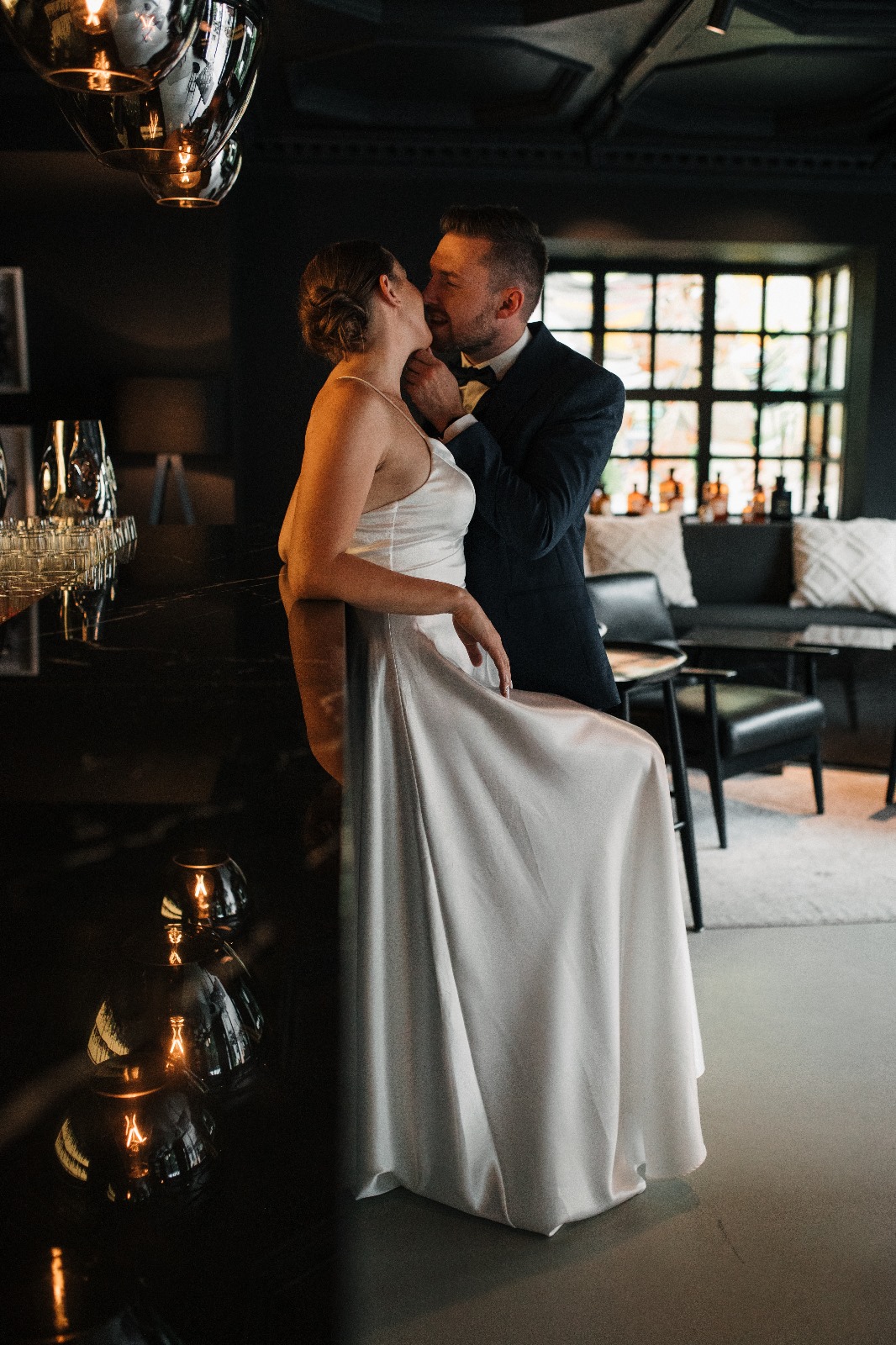 Braut auf einem Barhocker mit Bräutigam küssen sich, Hochzeitsplanung Deutschland, Lunaris Event Planning