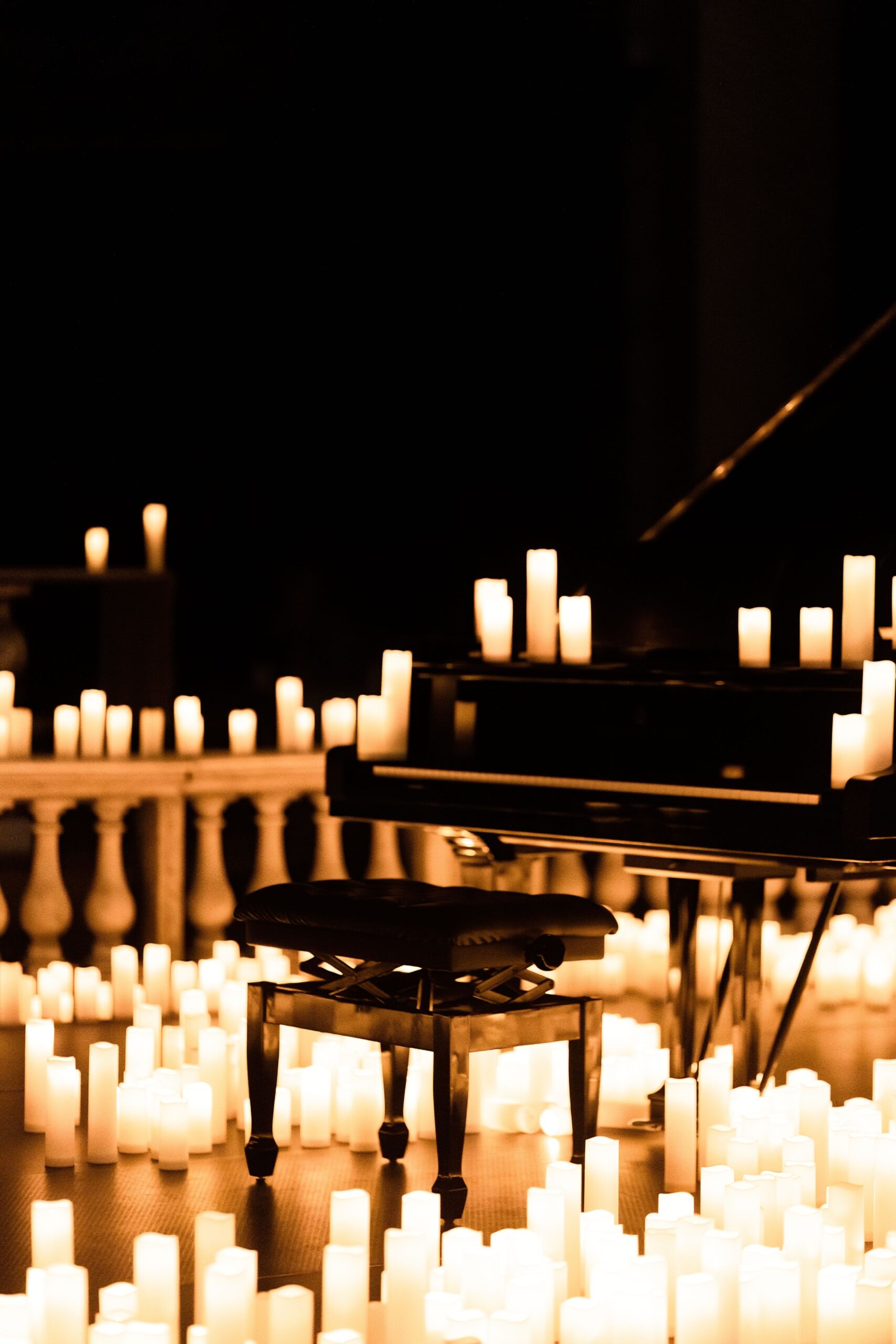 A chair and piano in a dark room surrounded by candles