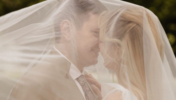 Brautpaar unter einem Schleier am lachen und küssen, Hochzeitsplanung Deutschland, Lunaris Event Planning